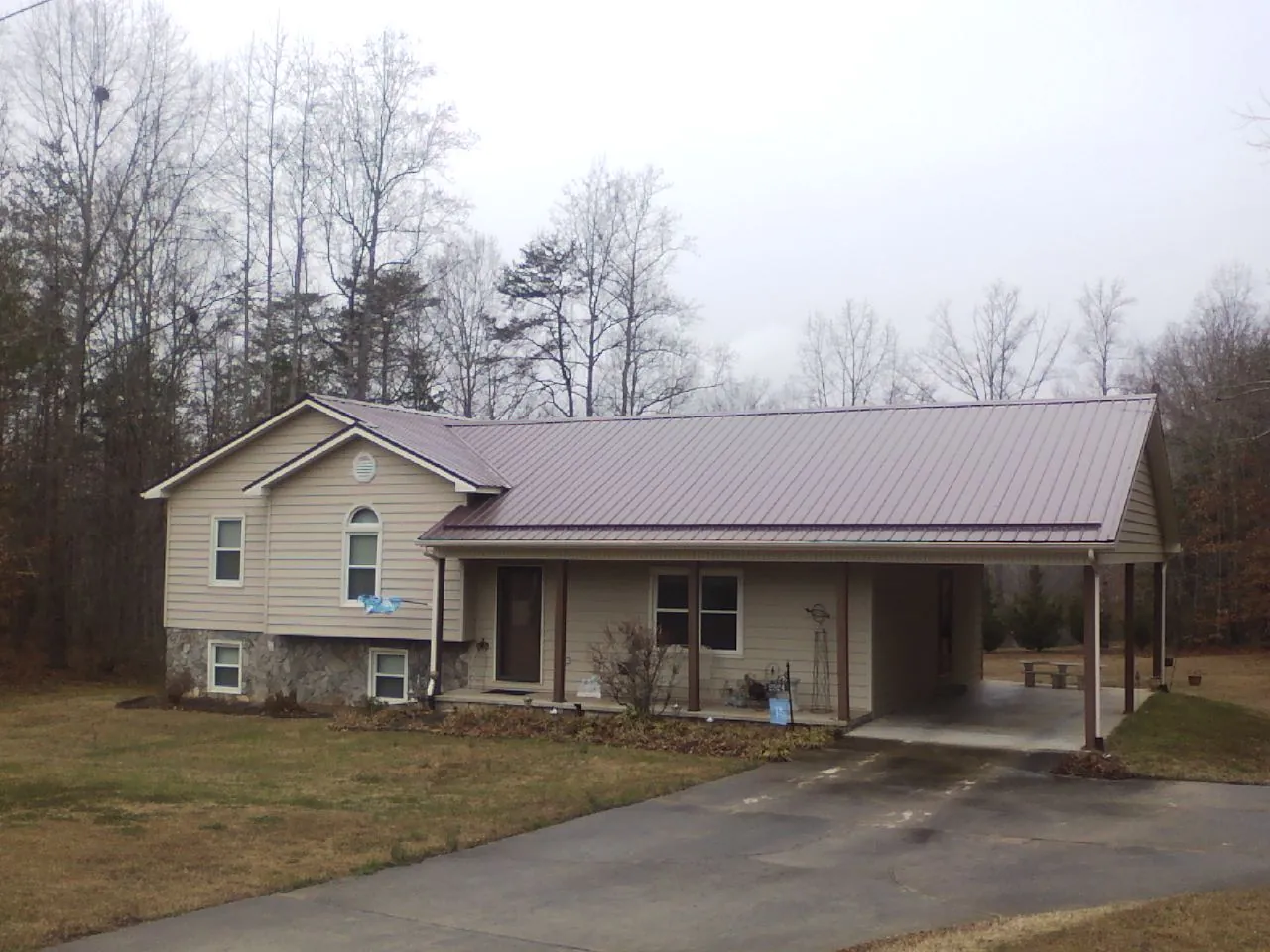 Burgundy metal roof on a tan split level home with an attached carport in Milford