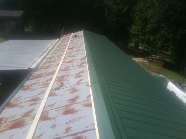 Old rusted panels beside newly installed green metal roofing — Wind Damage Roof Repair by Roofing Brothers in Milford