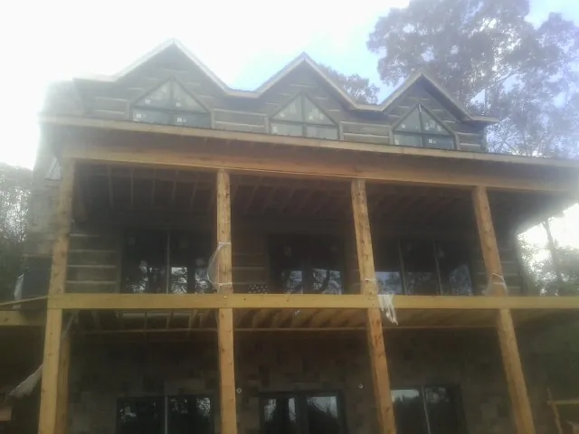 Dormers and porch framing on a large log home under construction — Roof Coating work by our crew in Milford